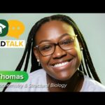 A woman with glasses smiles at the camera. Text reads: GRAD TALK. Isis Thomas, PhD, Biochemistry & Structural Biology. A graduation cap and chat bubble icon are shown.